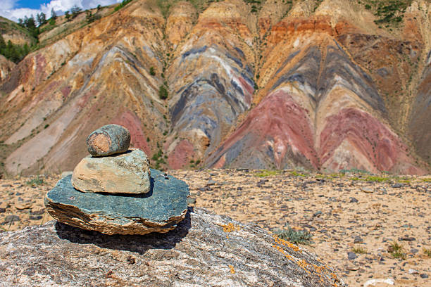 Stone cairn on boulder against multi-colored Mars mountains at Altai Republic, Russia. Altai Mars mountains near village of Chagan-Uzun in the valley of Kyzylchin River