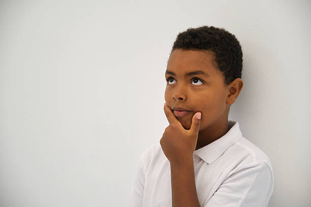Young, curious student is deep in thought, contemplating a question with his hand on his chin