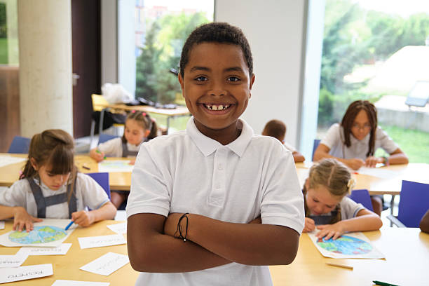 istock Portrait of smiling elementary school student with classmates drawing in background 2229342019