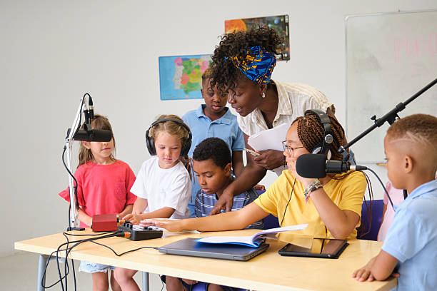 Elementary school students recording a podcast with their teacher