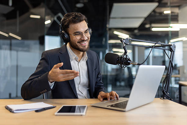 istock A smiling businessman podcasts from his modern office using a microphone and laptop. 2229349362