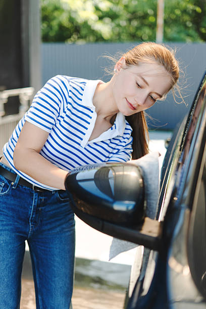 istock Young woman washing her car with a microfiber cloth 2229349430