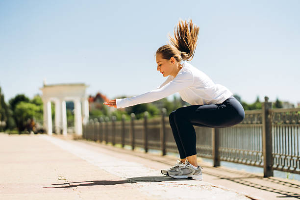 istock Young sporty woman doing squats outdoors in urban environment 2229349531
