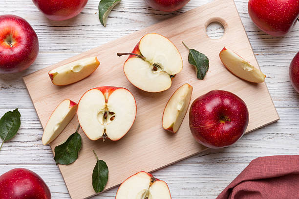 Fresh red apples with green leaves on table. cutting board with knife. Top view.