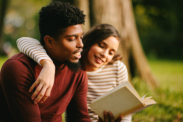 istock Couple reading book together outdoors in park 2229358657