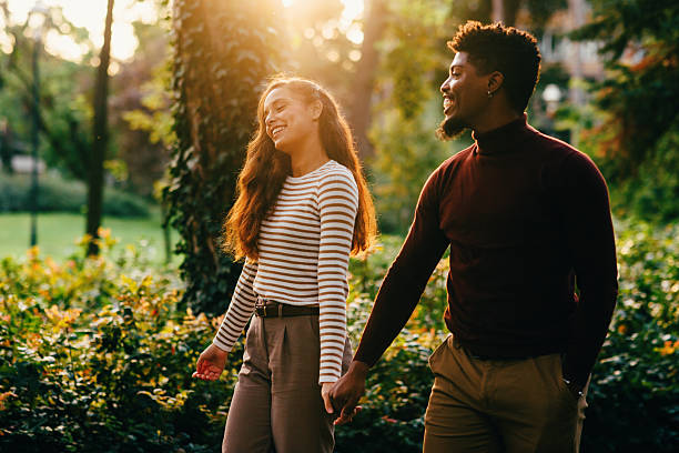 istock Happy couple holding hands and walking in park during sunset 2229358705