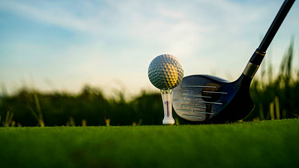 istock Golf Ball on Tee with Club Ready for Swing at Sunset Horizon 2229362973