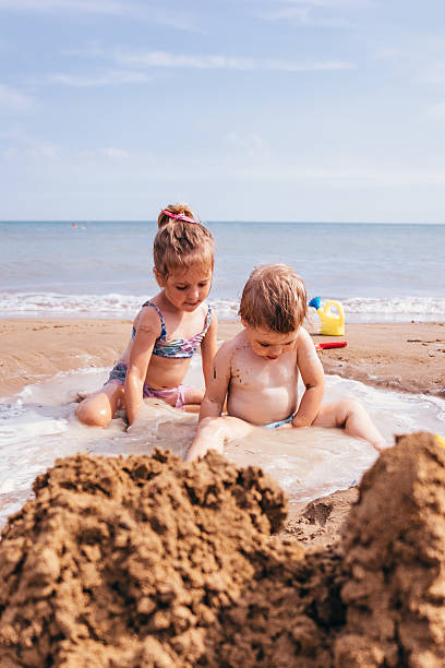 istock Two girls watching sea foam on the shore 2229363451