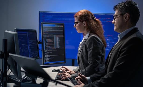 istock Dedicated professionals working in tandem at multiple screens in a bright tech workspace. 2229363506