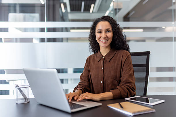 istock Smiling woman working on laptop in modern office environment with professional style. 2229365614