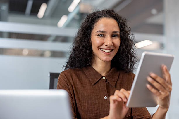 istock A smiling woman holds a tablet, working in a modern office environment with ease. 2229365629