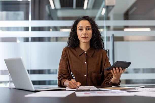 istock Focused businesswoman calculating finances and working on documents at her desk. 2229365637