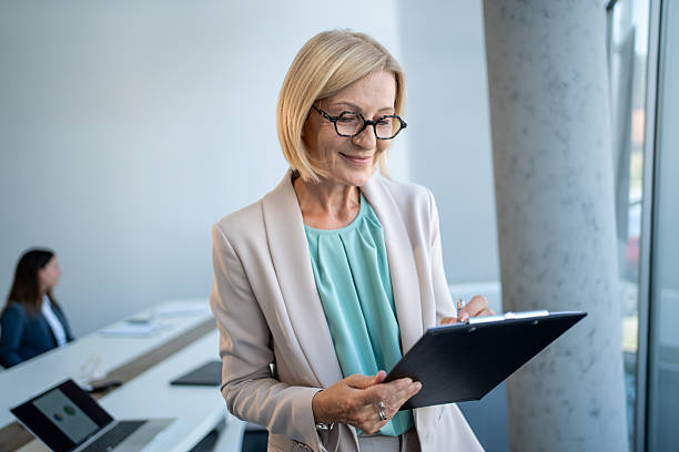 istock Senior businesswoman taking notes on clipboard in modern office 2229366589