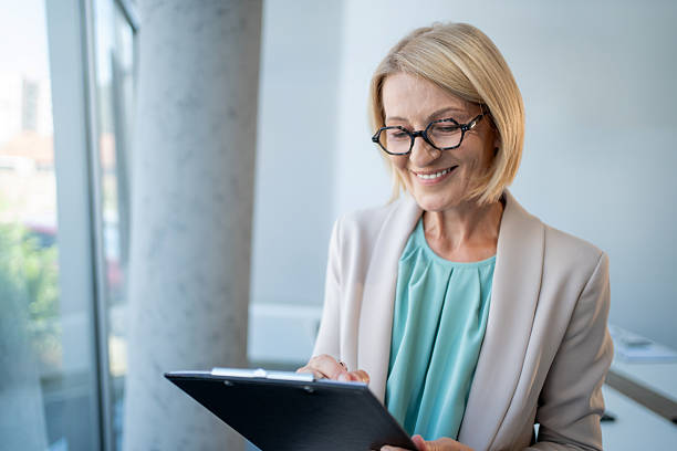 istock Smiling senior businesswoman taking notes on clipboard in office 2229366594