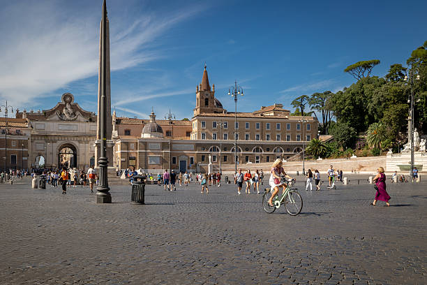 Rome, Italy - August 4, 2025: A woman cycles through the historic city center, in Piazza del Popolo, in the traffic-free zone.