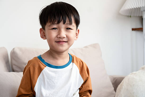 istock smiling Asian boy sits comfortably on a sofa at home 2229369821