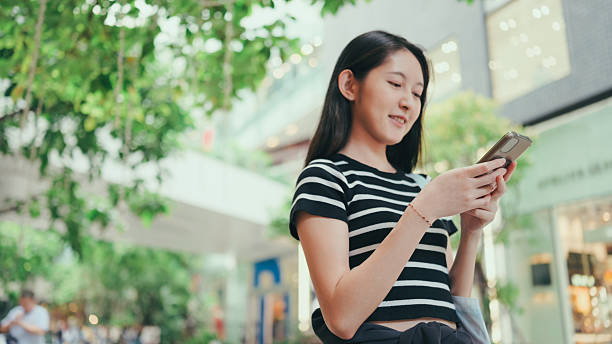 A young woman watching review video reading an article on her smartphone while enjoying mobile online purchasein her e-commerce platform
