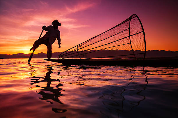 Fisherman posing during the sunset on Inle Lake. Leg-rowing fishermen on Inle Lake are a major tourist destination in Myanmar (Burma).