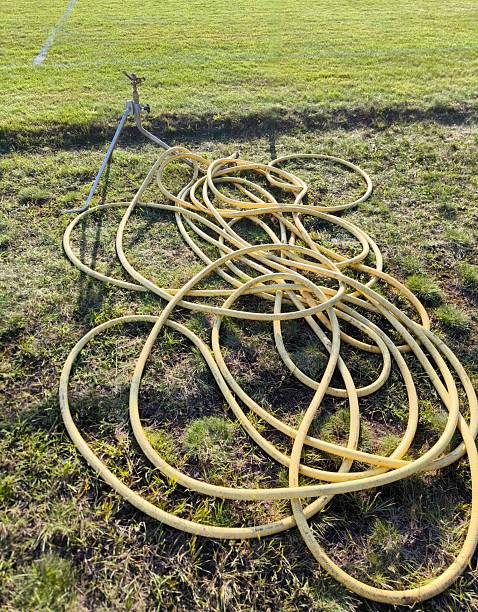 istock Tangled garden hose with sprinkler on green lawn 2229374868