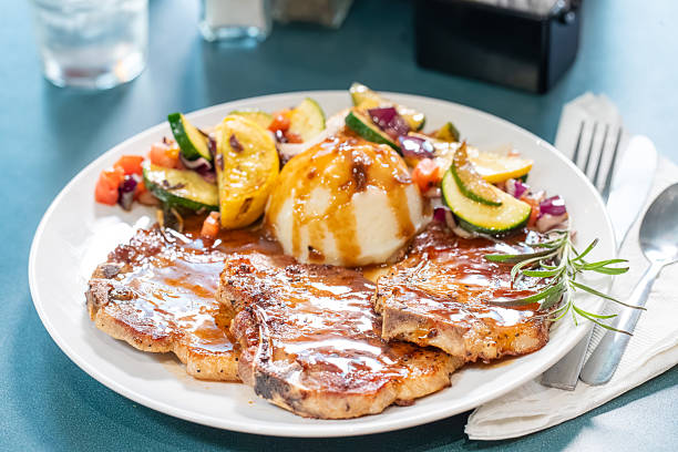 istock bourbon pork chops. mashed potatoes and grilled veggies in a restaurant setting 2229376611