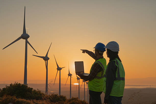 istock Young maintenance engineer team working in wind turbine farm at sunset 2229378354