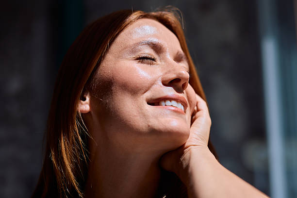 Woman enjoying sunlight with closed eyes and smiling