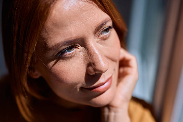 istock Pensive redhead woman looking up, enjoying sunlight on her face 2229380420
