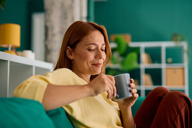 istock Serene woman enjoying a hot beverage on a comfortable sofa at home 2229380447