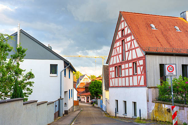 Rossdorf, Germany - June 23, 2025: Quaint street view in Rossdorf, Germany, featuring traditional half-timbered houses and modern buildings under a cloudy sky.