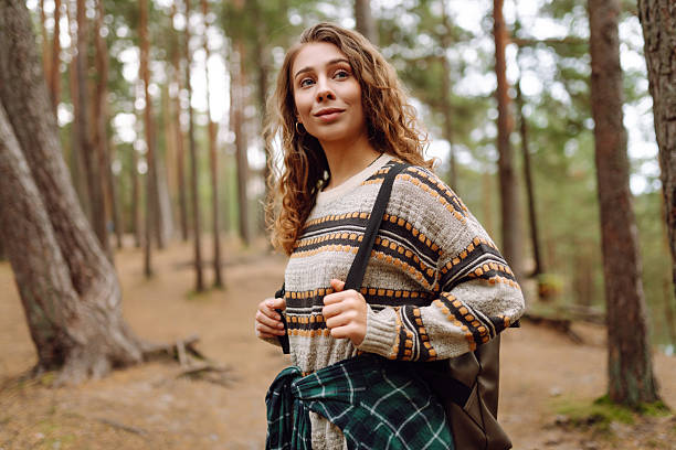 istock A cute woman is sitting on a log in a quiet forest. 2229394968