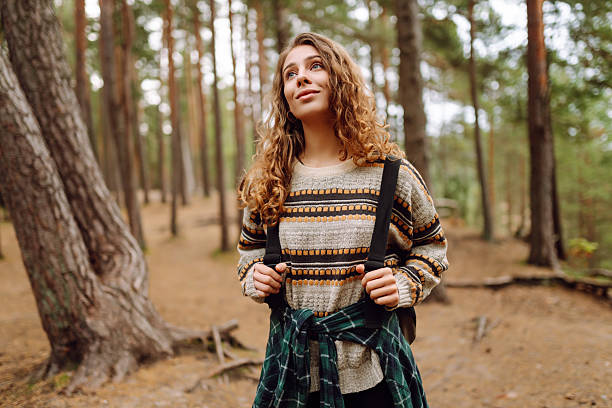 istock A cute woman is sitting on a log in a quiet forest. 2229394972