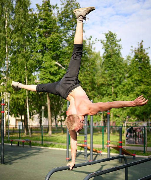 Group of strong young men with naked torsos takes part in morning workout at outdoors gym in a public park. Shooting in summer sunny morning