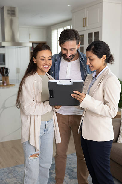 istock Real estate agent showing document to smiling couple 2229398901