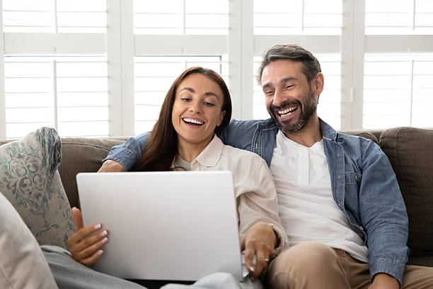 istock Joyful couple sits together on cozy sofa with laptop 2229399106