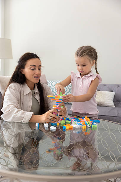istock Mother and daughter playing stacking game building tower with blocks 2229401240