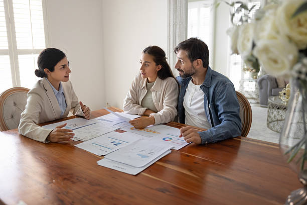 istock Professional consultant meets with couple at table covered with documents 2229402429