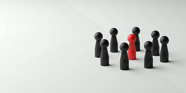 istock Leadership, focus on a key individual, unique idea, or highlighted person in a group. A single red doll standing in the middle of a small circle of black dolls on a clean, light background. 2229402600