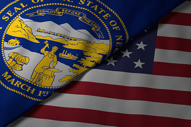 Close-up view of the Nebraska state flag alongside the United States national flag. The vibrant colors and fabric texture highlight the unity and identity of the state within the nation.