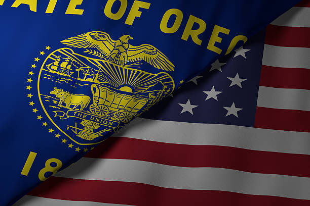 Close-up view of the Oregon state flag alongside the United States national flag. The vibrant colors and fabric texture highlight the unity and identity of the state within the nation.