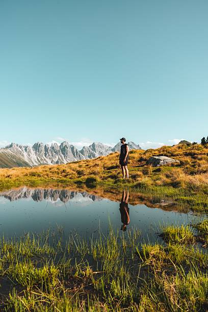 istock Person by a Reflective Pond with Mountain Views 2229409214