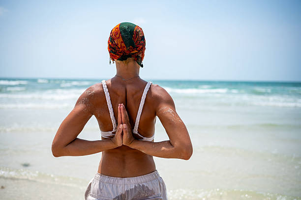 A girl at the beach, holding a sunhat in her hand.