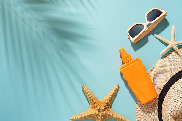 istock Sunscreen, sunglasses and seashell on blue background with hard sunny shadows. 2229412491