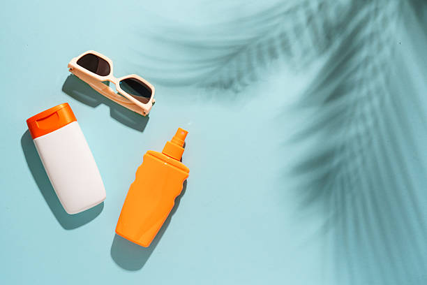 istock Sunscreen, sunglasses and seashell on blue background with hard sunny shadows. 2229412494