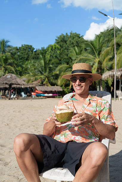 Hispanic man tourist sitting and using phone while having coconut water drink