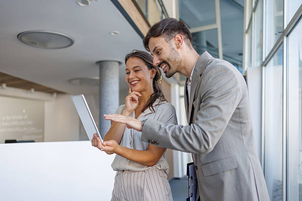 istock Two businesspeople smiling and looking at a tablet in a modern office 2229413775