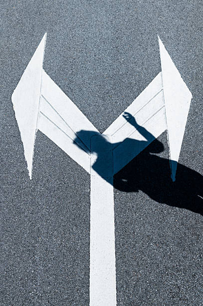 Two directional arrow symbol on asphalt road with people shadow