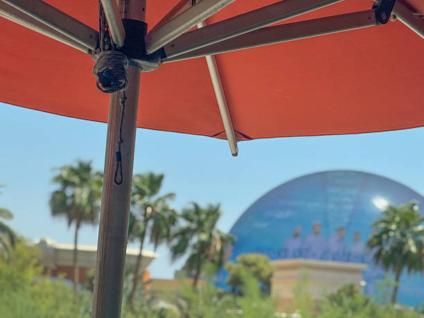 under panel of orange umbrella in las vegas summer sun with round building in background