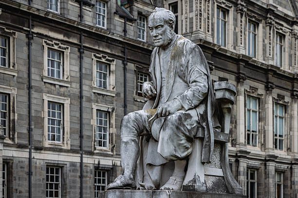 Dublin, Ireland - June 09 2025 : George Salmon statue in front of the blurred background of the Graduates Memorial Building from Library Square, Trinity College, Dublin, Ireland