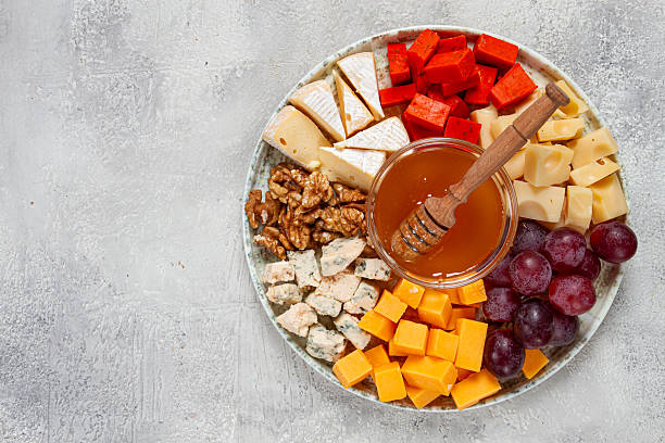 istock Appetizer, assorted cheese, with nuts and honey, on a round plate, top view, no people, 2229427420