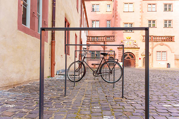 Darmstadt, Germany - June 5, 2025: Bicycle secured to a minimalist bike rack in a picturesque cobbled square surrounded by historic buildings in Darmstadt, Germany.